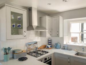 eine Küche mit weißen Schränken und einem Herd mit Backofen in der Unterkunft The Ferryman in Weymouth + 8 Fotos