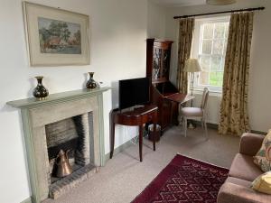 a living room with a fireplace and a desk at Pear Cottage - Priorwood Garden in Melrose