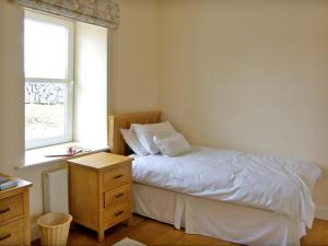 a bedroom with a white bed and a window at Dolmen Cottage in Kilfenora