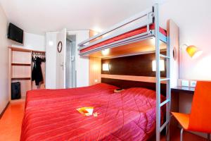 1 dormitorio con litera y colcha roja en Premiere Classe Valenciennes Sud - Rouvignies, en Valenciennes
