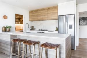 a kitchen with a large white counter with stools at Harbourview Haven in Raglan