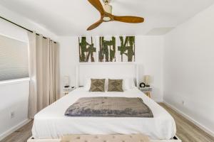 een slaapkamer met een wit bed en een plafondventilator bij Newly Renovated Condo Stand Up Paddle Boards Included! in Kailua-Kona