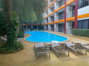 einen Pool mit Tischen und Stühlen vor einem Gebäude in der Unterkunft AYA APARTMENTS IN MBC in Mai Khao Beach