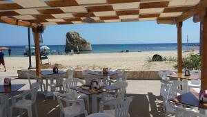 ein Restaurant mit weißen Stühlen und Tischen am Strand in der Unterkunft Cuore di mare SALENTO - Beach House for Families in Torre Pali 