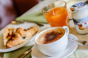 a cup of coffee on a table with a plate of food at Albergo Alla Posta in Trieste