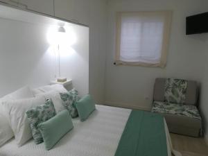 a white living room with a couch and a window at Alo Baía São Lourenço in Santa Bárbara