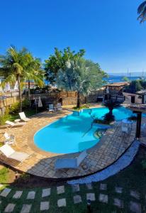 a swimming pool in a resort with palm trees at Monalisa Guesthouse Pé na Areia Ilhabela in Ilhabela