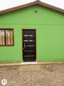 un edificio verde con una puerta negra. en Hospedaje El TaTa en Colonia Las Rosas