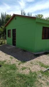 a green building with a door in a yard at Hospedaje El TaTa in Colonia Las Rosas