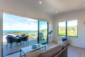 a living room with a couch and a large window at Marama Cottages with ocean views in Oneroa