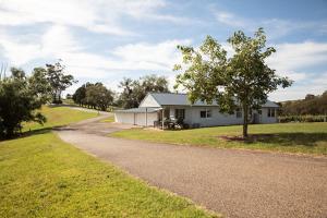 a white house with a tree and a road at Audrey Wilkinson Vineyard in Pokolbin