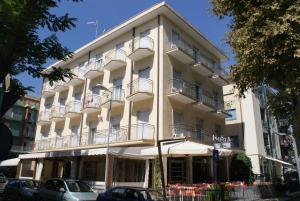 里米尼Hotel Londra的一座白色的建筑,其前设有阳台和桌子