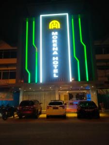 a lit up building with cars parked in front of it at Hotel Morena Batam in Batam Center
