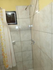 La salle de bains est pourvue d'une douche avec une porte en verre. dans l'établissement Hospedaje El TaTa, à Colonia Las Rosas