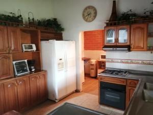 a kitchen with a white refrigerator and a clock on the wall at Hotel Cabañas De Rozo in Rozo