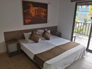 a bedroom with a bed with a painting on the wall at Hotel Cabañas De Rozo in Rozo