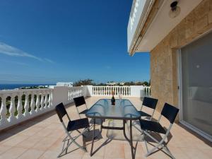 Un patio con una mesa y sillas en un balcón. en SEA CAVES suite, en Peyia
