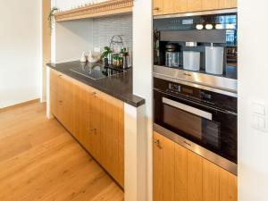 uma cozinha com armários de madeira e um balcão preto em Luxurious Crystal Sea View apartment with 2 terraces em Oostende
