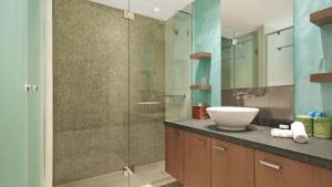 a bathroom with a sink and a glass shower at Penthouse - Palm Cove in Palm Cove