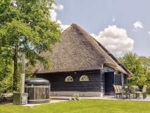 a black house with a thatched roof with a grill at Tranquil Farmhouse in Rijsbergen with Hot Tub and Garden in Rijsbergen