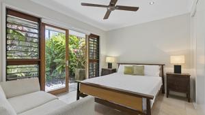 a bedroom with a bed and a couch and a window at Larasati - Palm Cove in Palm Cove +11 photos