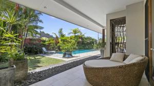 an outdoor patio with a wicker chair and a pool at Larasati - Palm Cove in Palm Cove