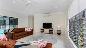 a living room with a couch and a tv at Sandcastles - Palm Cove in Palm Cove