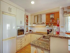 cocina con armarios blancos y nevera blanca en Belvilla by OYO Casa Amarilla Blanca, en Salobreña
