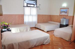 a hotel room with three beds and a television at Hotel Bahia Blanca Santa Marta Frente al Mar in Santa Marta