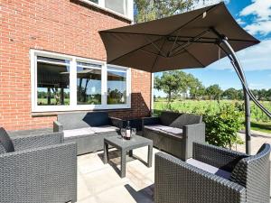 um pátio com um guarda-sol, cadeiras e uma mesa em Relaxing Holiday Home in Hellendoorn with Garden em Hellendoorn