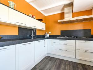 uma cozinha com armários brancos e uma parede laranja em Relaxing Holiday Home in Hellendoorn with Garden em Hellendoorn