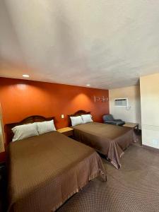 Habitación de hotel con 2 camas y pared de color naranja en Red River Inn, 