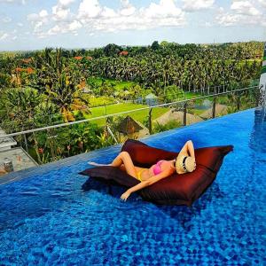 a woman laying on a pillow in a swimming pool at MaxOneHotels at Ubud - CHSE Certified in Ubud