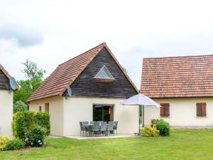 een huis met een schuin dak met stoelen en een parasol bij Holiday home at Lacapelle Marival in Lacapelle-Marival