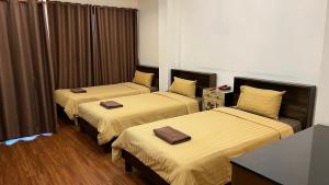 巴吞他尼Hotel IYA的配有棕色窗帘的酒店客房内的两张床