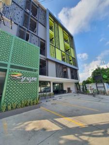 ein Gebäude mit grünen und gelben Fenstern und einem Parkplatz in der Unterkunft 3Season in Chiang Mai