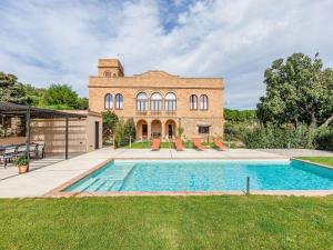 a brick house with a swimming pool in front of it at Belvilla by OYO Masmore petit Vulpellac in Vulpellac