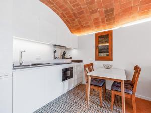 cocina con armarios blancos, mesa y sillas en Belvilla by OYO Masmore petit Vulpellac, en Vulpellach