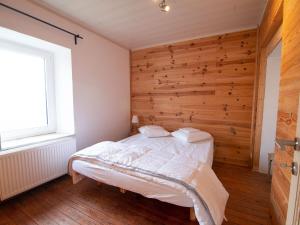 Cama en habitación con pared de madera en Very spacious house with sauna spa and countryside views, en Gouvy