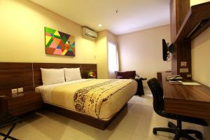 a hotel room with a bed and a desk and a desk at Prasada Mansion Sudirman in Jakarta