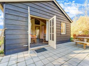 Une petite maison avec une porte s'ouvre sur une terrasse. dans l'établissement Delightful Holiday Home in Lage Zwaluwe with Garden, à Lage Zwaluwe