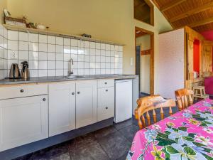- une cuisine avec des placards blancs, un évier et une table dans l'établissement Delightful Holiday Home in Lage Zwaluwe with Garden, à Lage Zwaluwe