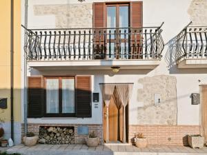 a house with a balcony and a wooden door at Belvilla by OYO Sirente House in Aielli