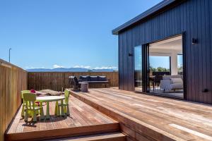 una terraza de madera con mesa y sillas en una casa en Hey Syrah Syrah!, en Martinborough