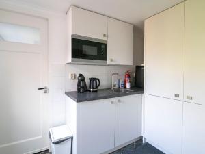 a white kitchen with white cabinets and a microwave at Appealing Holiday Home in Medemblik with Garden in Medemblik