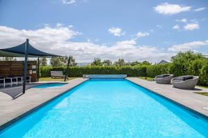 una piscina con dos sillas y una sombrilla en Hey Syrah Syrah!, en Martinborough