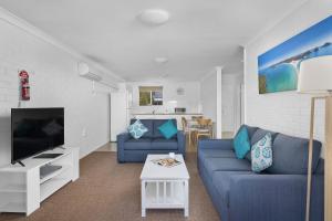 a living room with a blue couch and a tv at Seaside Holiday Resort in Fingal Bay