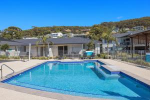 a swimming pool in front of a house at Seaside Holiday Resort in Fingal Bay