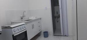 a white kitchen with a stove and a sink at LOFT in Iguaba Grande