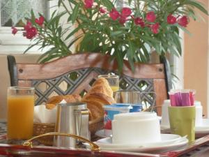 - une table de petit-déjeuner avec du pain, du jus d'orange et des fleurs dans l'établissement The Originals Boutique, Hôtel Clos Sainte Marie, Nevers, à Nevers
